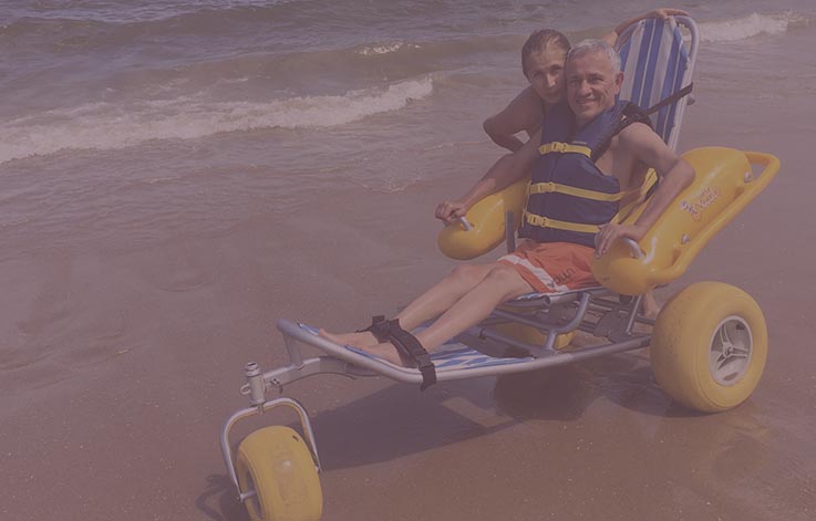 Persona en playa montada en silla de ruedas náutica